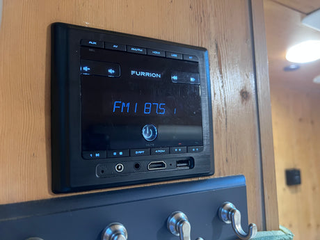 Furrion RV entertainment system, ideal for an rv rental, displays FM 87.5 with AUX, USB, and HDMI ports visible.