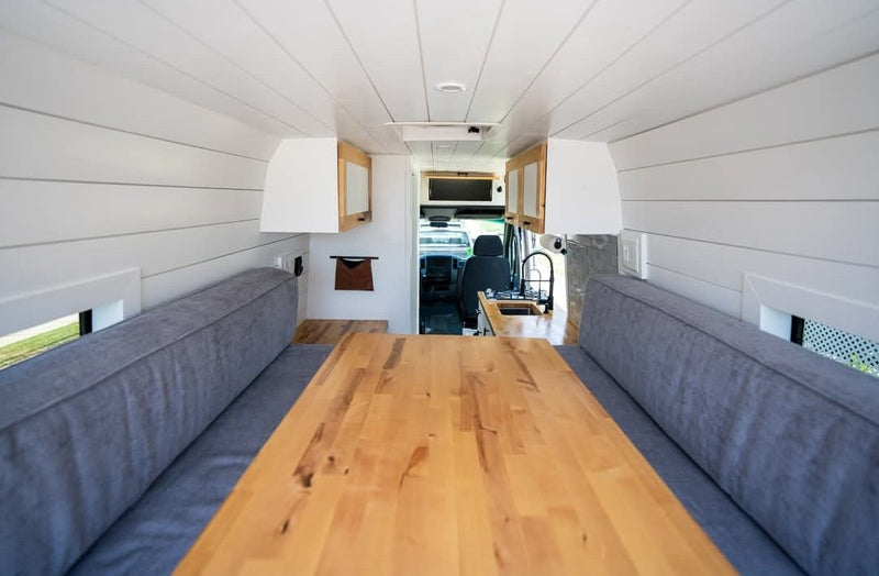 Modern RV rental interior: bright camper van dining area with wooden table, cozy benches, and compact kitchen setup. — photo 17