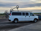 White conversion van with roof rack & rear bike rack, carrying multiple bicycles, suggesting an RV rental for outdoor adventures.