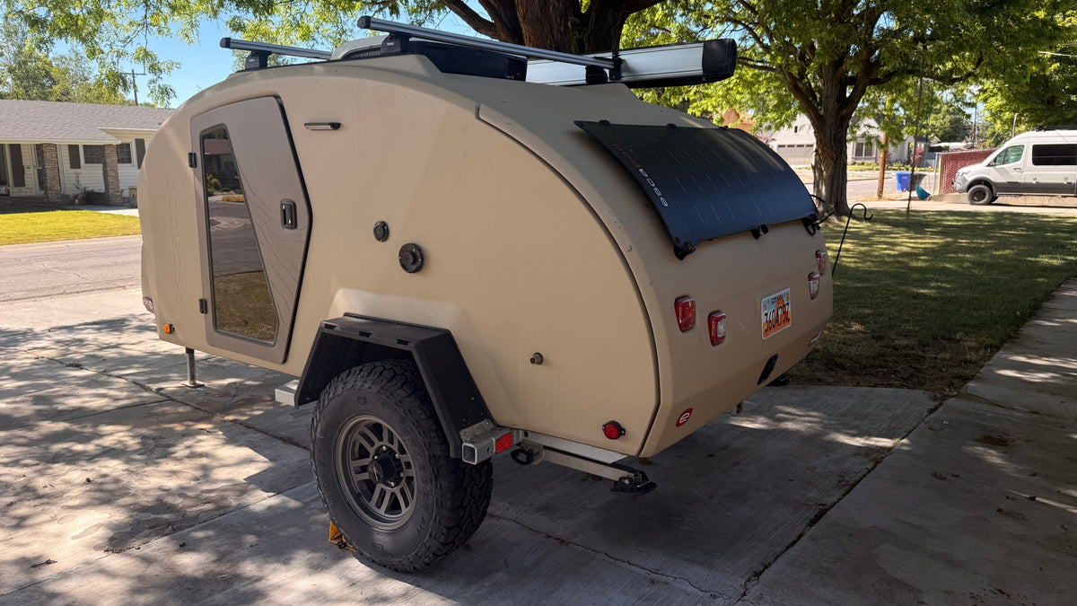  is a great rv rental option for adventures.|Rear view of a tan Escapod TOPO 2 teardrop RV rental with a solar panel — photo 11