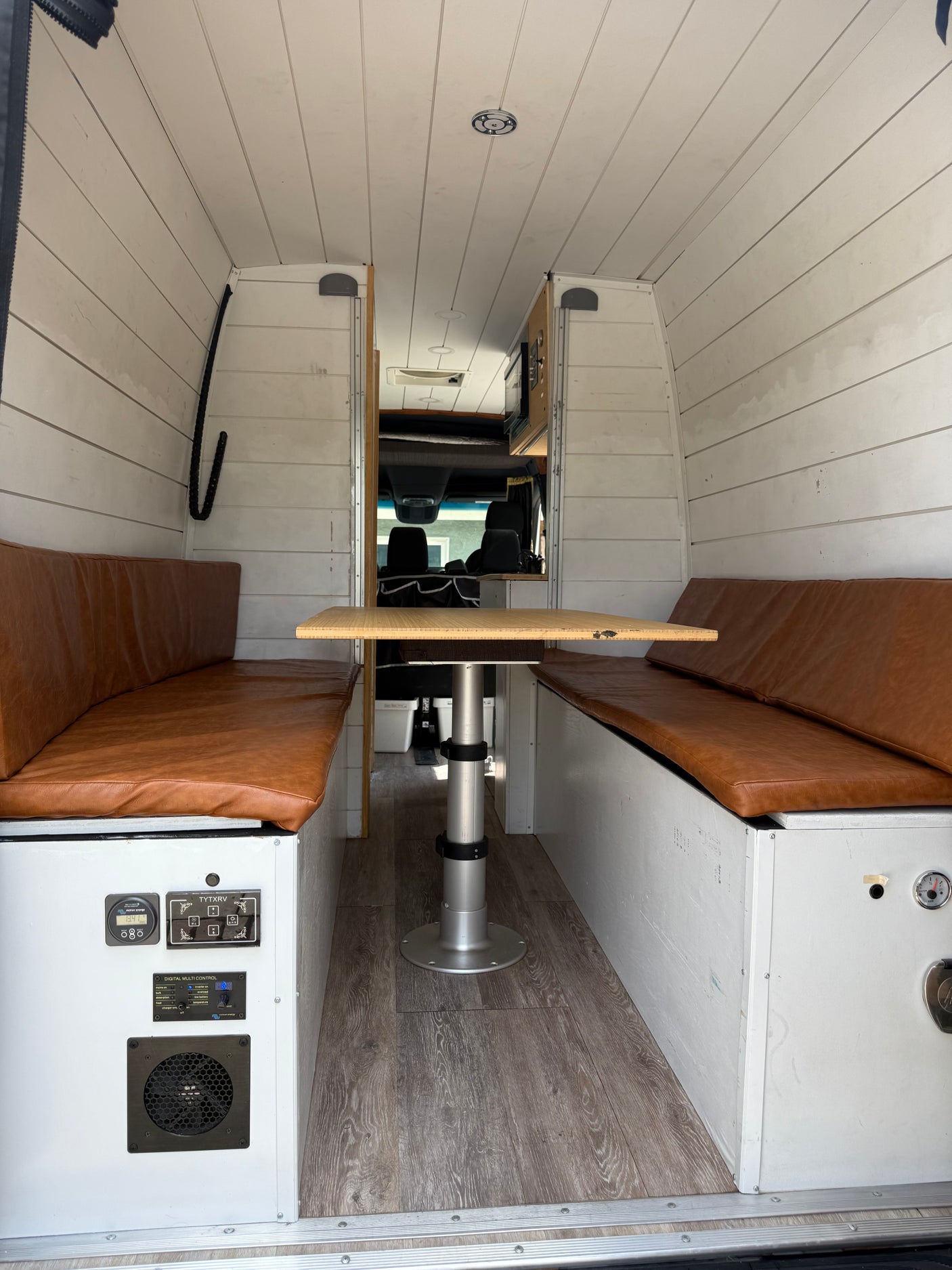 Step into this rv rental's inviting dinette, featuring leatherette benches, an adjustable table, and functional control panels.