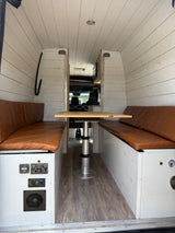 Step into this rv rental's inviting dinette, featuring leatherette benches, an adjustable table, and functional control panels.