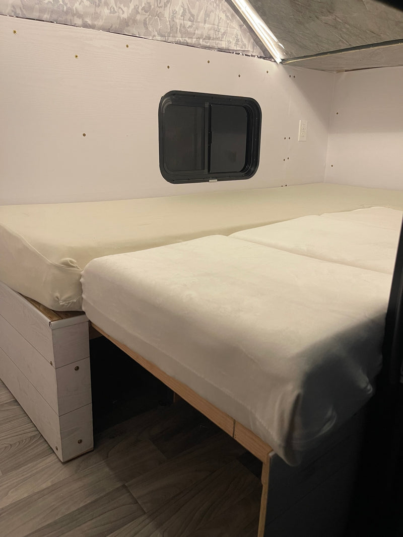 RV rental interior: Camper bed setup with two mattresses, a window, and a patterned pop-top ceiling. — photo 8