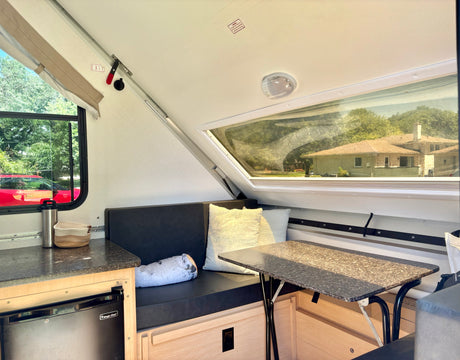 Compact A-frame rv rental interior: dining nook, Magic Chef fridge, and bright windows.