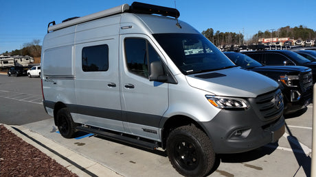 Silver Winnebago Revel camper van, ideal for RV rental adventures, parked outdoors on a sunny day.