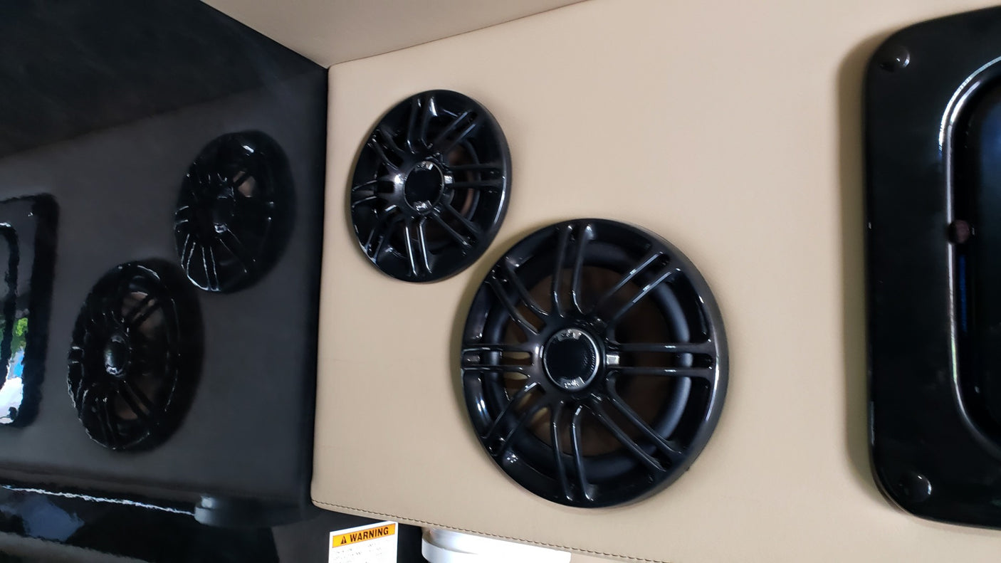 Black speakers mounted on beige and glossy black panels inside an RV rental. Enhanced audio for your adventures.