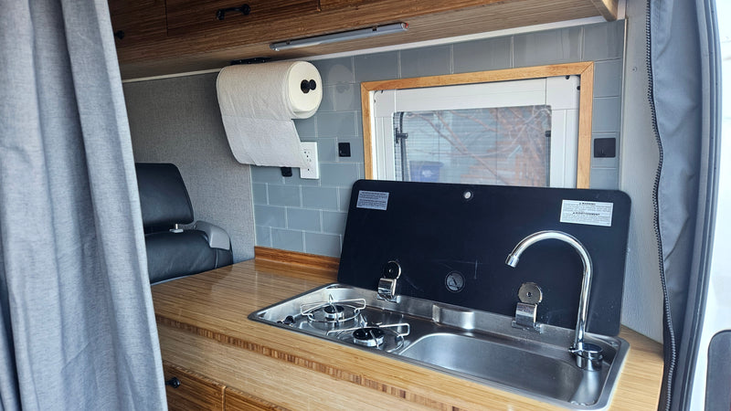 Inside an RV rental: a compact kitchen with a two-burner stove, sink, and bamboo counter. Ready for adventures! — photo 3