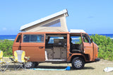 This brown VW camper van with pop-top roof and open interior offers an ideal rv rental for beach camping.