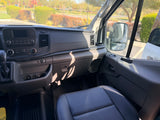 Inside an RV rental van, showing the passenger seat, dashboard controls, and outside view on a sunny day.