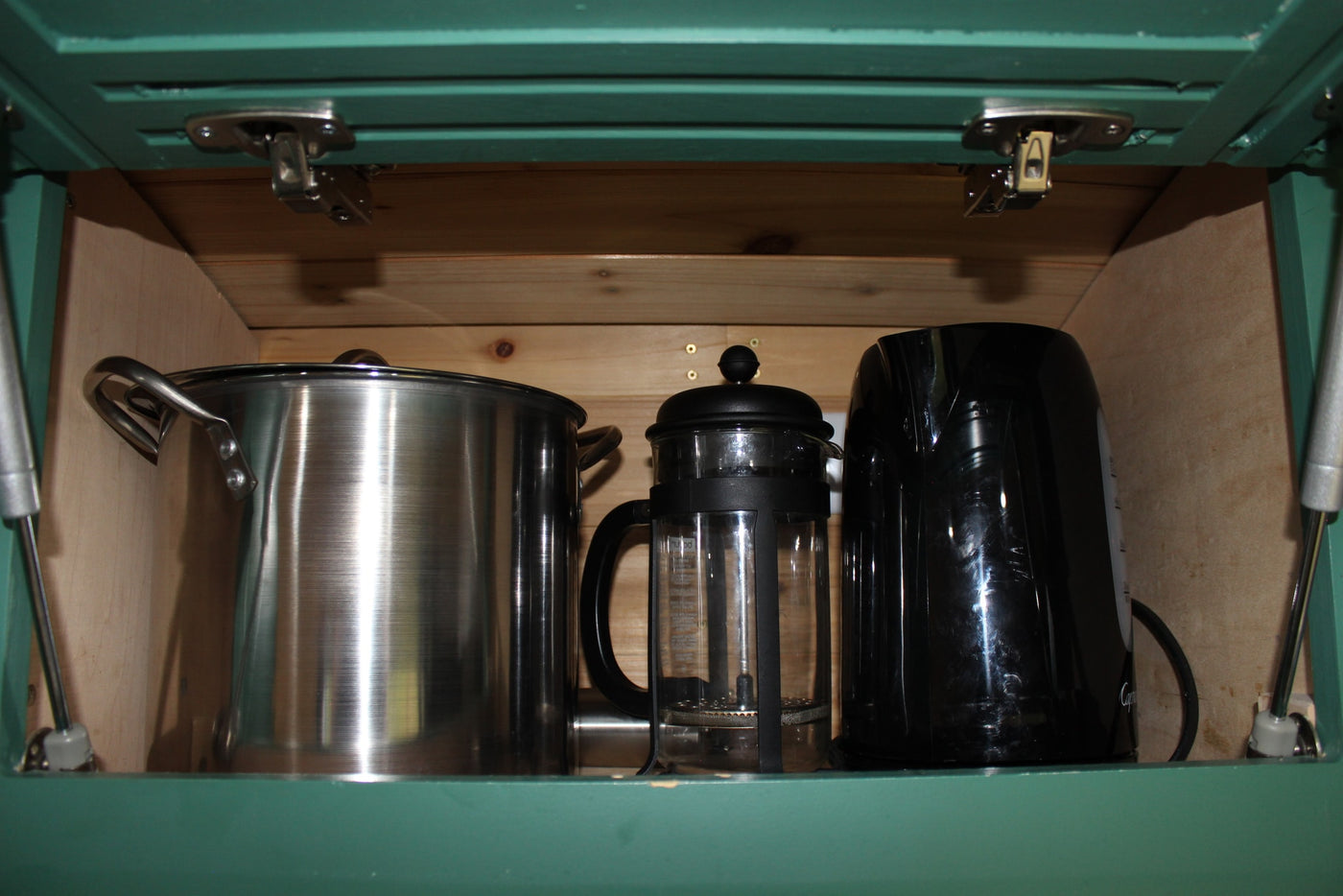RV rental kitchen cabinet showing a stainless pot, glass French press, and black electric kettle for convenient cooking and coffee. — photo 4