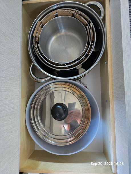 Organized kitchen drawer in an RV rental with stacked pots, pans, and a lid for easy access.