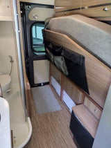 Explore this versatile RV rental interior with a raised bed, handy storage pockets, and a full compact bathroom.
