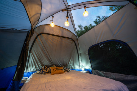 Cozy glamping tent interior with bed, ambient lights, and nature views, enhancing your RV rental camping adventure.