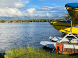 Stunning Alaskan lake view: floatplane by shore, mountains beyond. Ideal for your RV rental getaway.