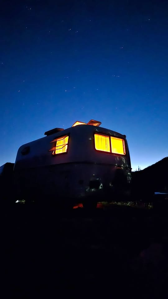 Experience starry nights in this cozy **rv rental**! Vintage camper glows warmly against the deep blue