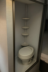 Compact RV rental wet bath featuring a toilet and space-saving corner storage shelves, optimized for small interiors.