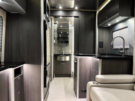 Inside a sleek rv rental: modern kitchen, compact bathroom vanity, and comfy seating in a contemporary design.