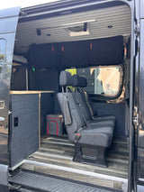 Inside an RV rental van: multi-person seating, durable flooring, smart storage, and a comfy bed area visible.