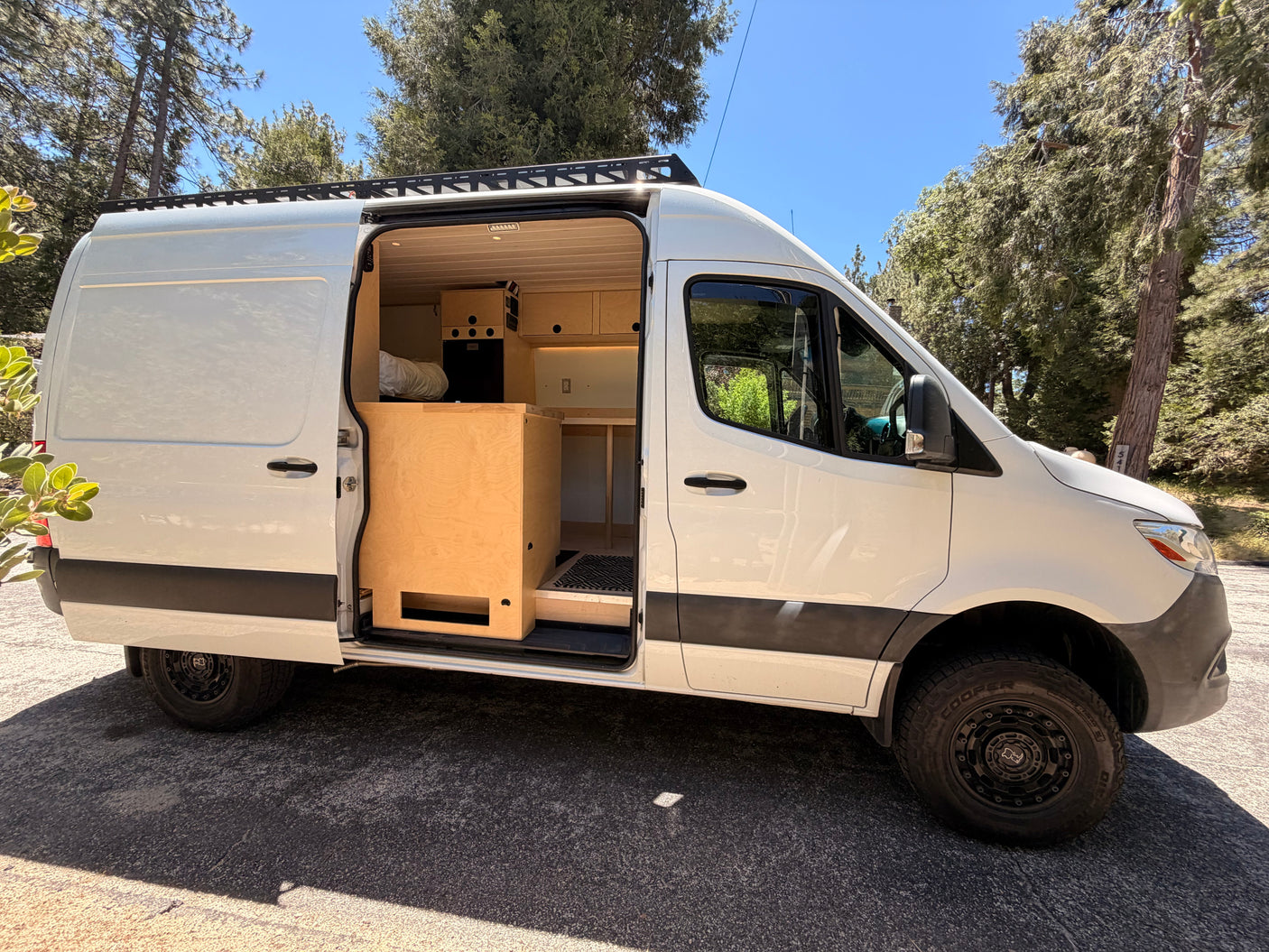 White custom camper van with open side door showcasing its wood interior. Ideal for your next RV rental adventure.