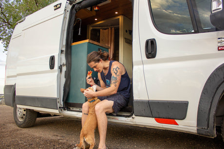 Cozy RV rental: man sharing pizza with his dog from their customized camper van, embracing van life travel.