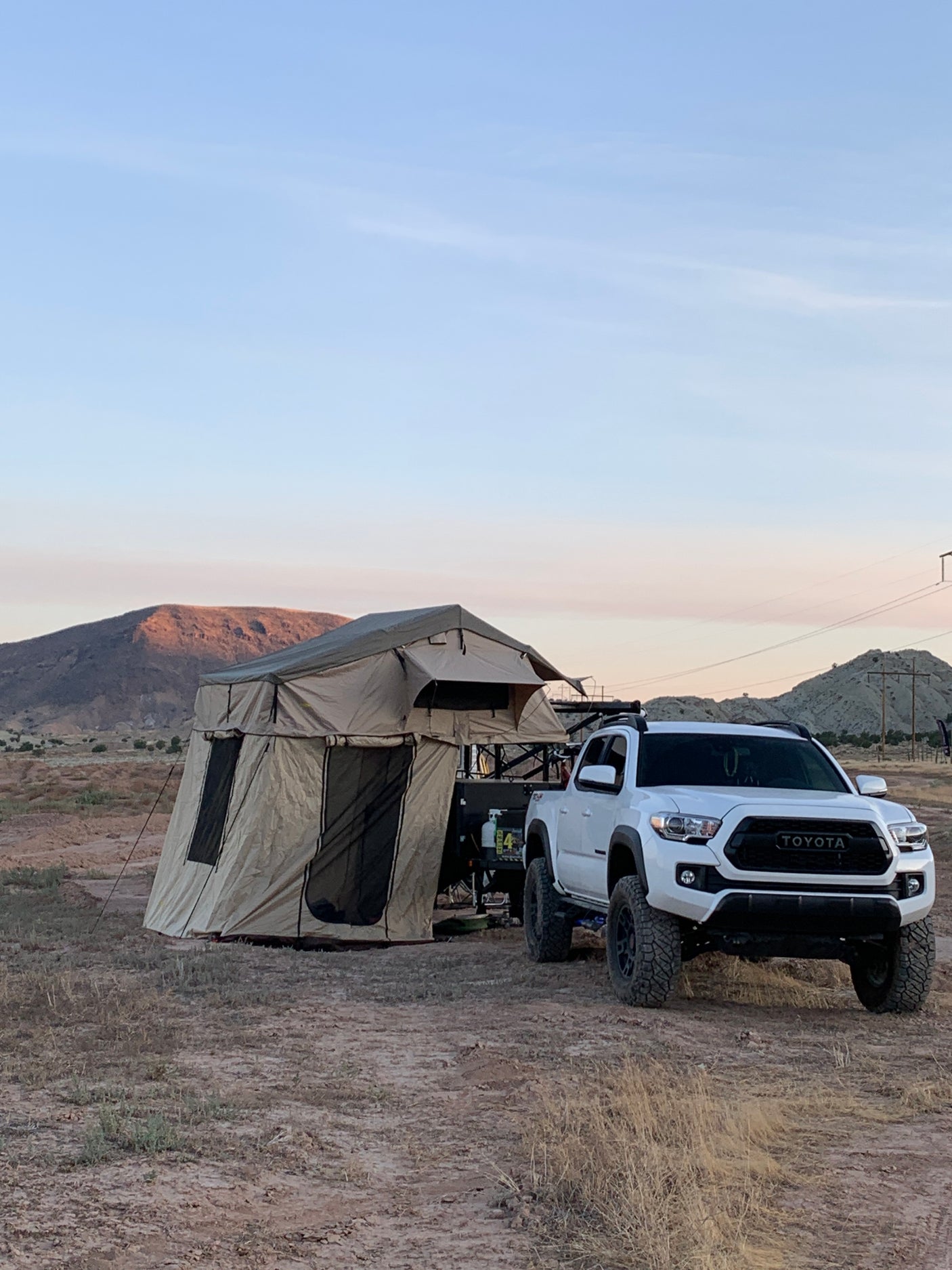 Overlanding adventure! White Toyota Tacoma with a rooftop tent, a great RV rental alternative for off-grid camping in nature.