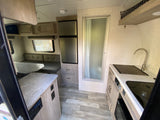 RV rental interior: A compact kitchen with sink/stove, dinette, refrigerator, and shower stall, ready for your next adventure.