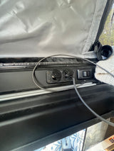 RV rental interior: close-up of power outlets (USB, 12V socket) and charging cable, useful for camper life.