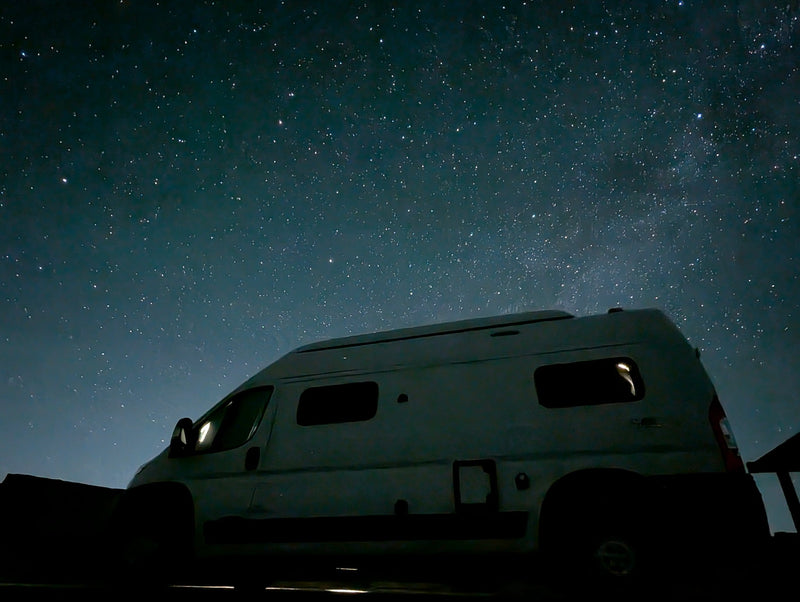  snow-dusted peaks under a clear blue sky.|White RV rental camper van parked on a gravel road — photo 3