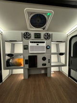 Modern RV rental interior featuring a ceiling fan, AC unit, speakers, solar control, and integrated storage for comfort and convenience.