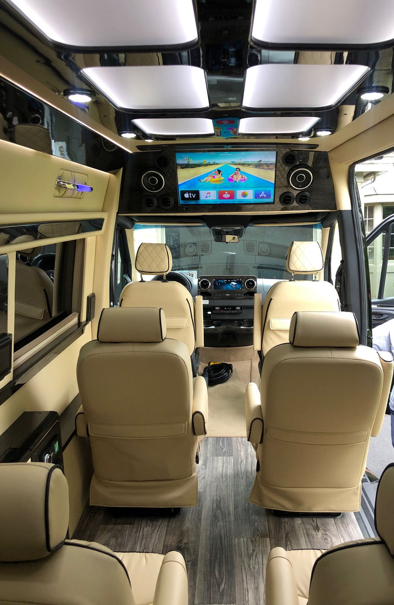 Plush RV rental interior: cream leather seats, wood-look floor, and a large screen displaying Apple TV content. — photo 20