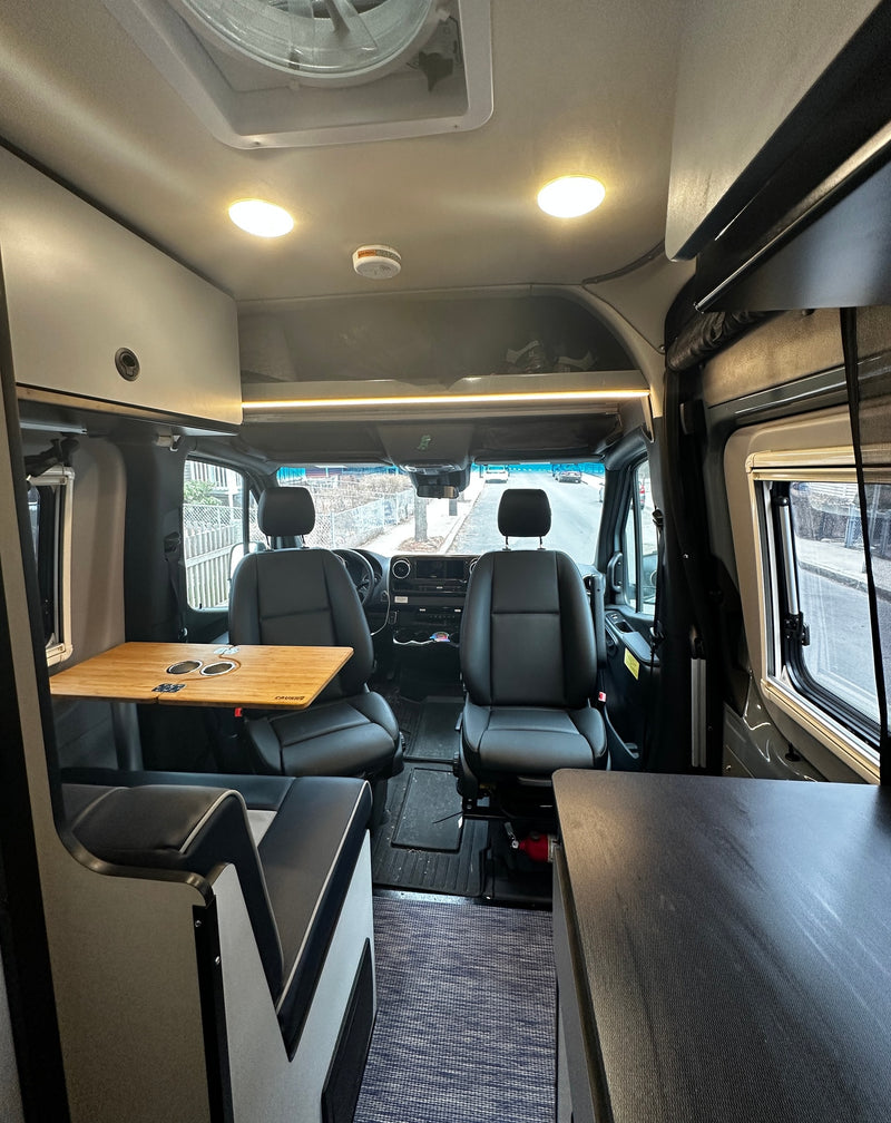 Inside this RV rental: a versatile camper van interior with front seats, side table, and overhead storage. — photo 12