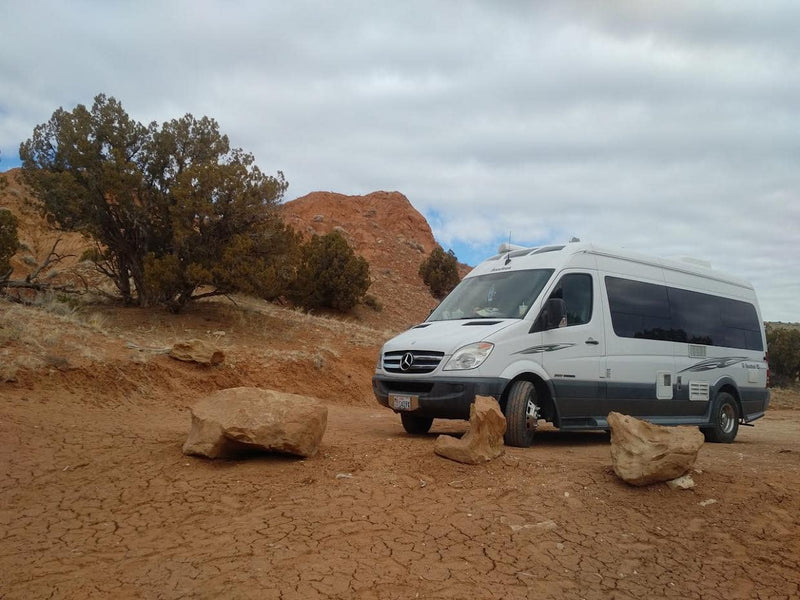White Roadtrek Sprinter RV rental parked on a cracked red dirt road — photo 1
