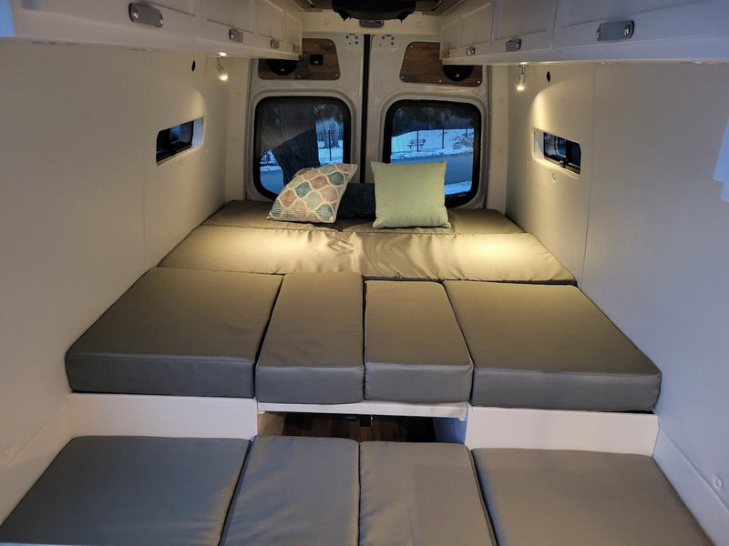 Comfortable camper van interior for your next RV rental adventure. Features modular grey bed cushions & cozy lighting. — photo 7