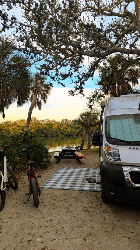 Enjoy a beautiful RV rental waterfront camping spot, complete with bikes, a picnic table, and palm trees. Perfect outdoor adventure!