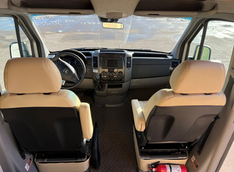 Spacious RV rental cockpit with tan seats, Mercedes-Benz dash, and a clear view. Fire extinguisher visible for safety. — photo 8