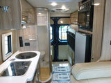 Step inside this compact RV rental, showcasing a functional kitchen, bathroom, microwave, fridge, and cozy seating area.