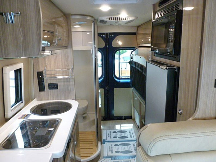 Step inside this compact RV rental, showcasing a functional kitchen, bathroom, microwave, fridge, and cozy seating area.