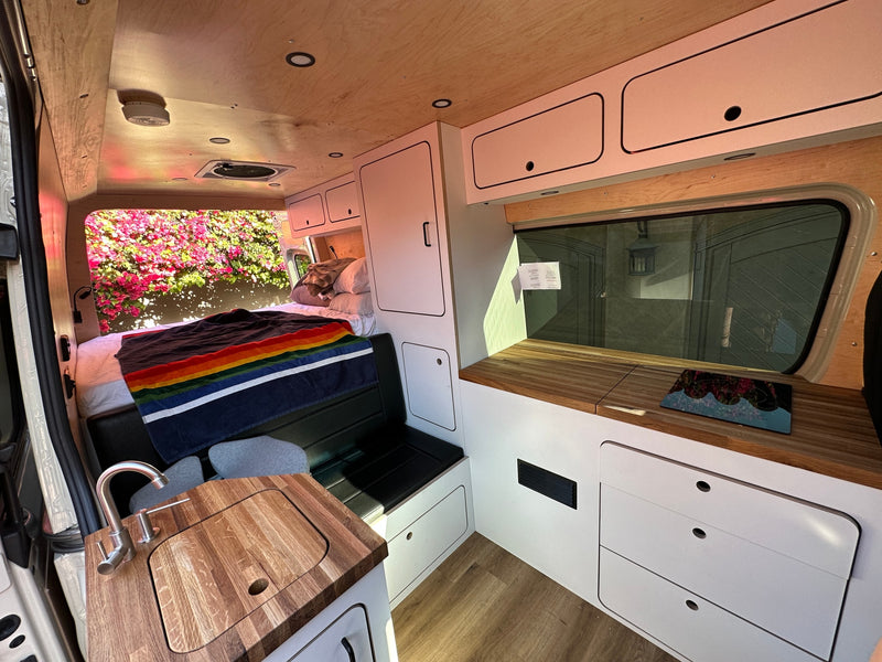 This inviting RV rental features a full bed, compact kitchen with sink, and custom cabinetry for comfortable travel. — photo 3
