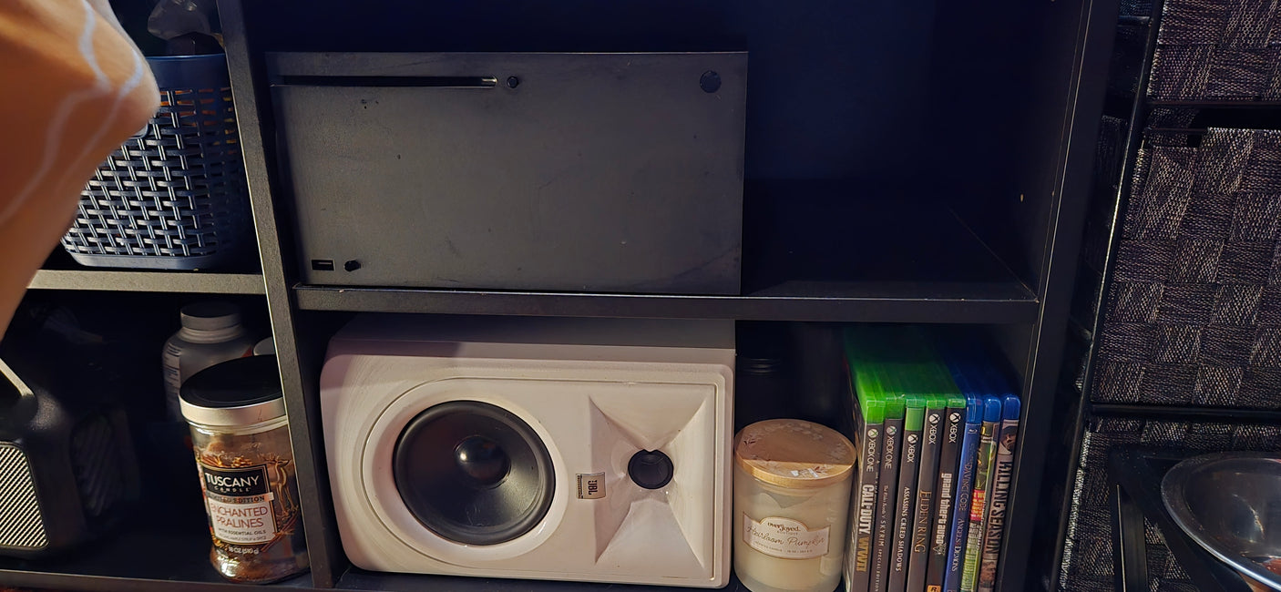 Organized shelf with Xbox, JBL speaker, games, and candles. Ideal for compact spaces or an RV rental setup.