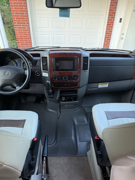 Get a look inside this RV rental, featuring its detailed dashboard, steering wheel, front seats, and a shotgun on the driver's side floor.