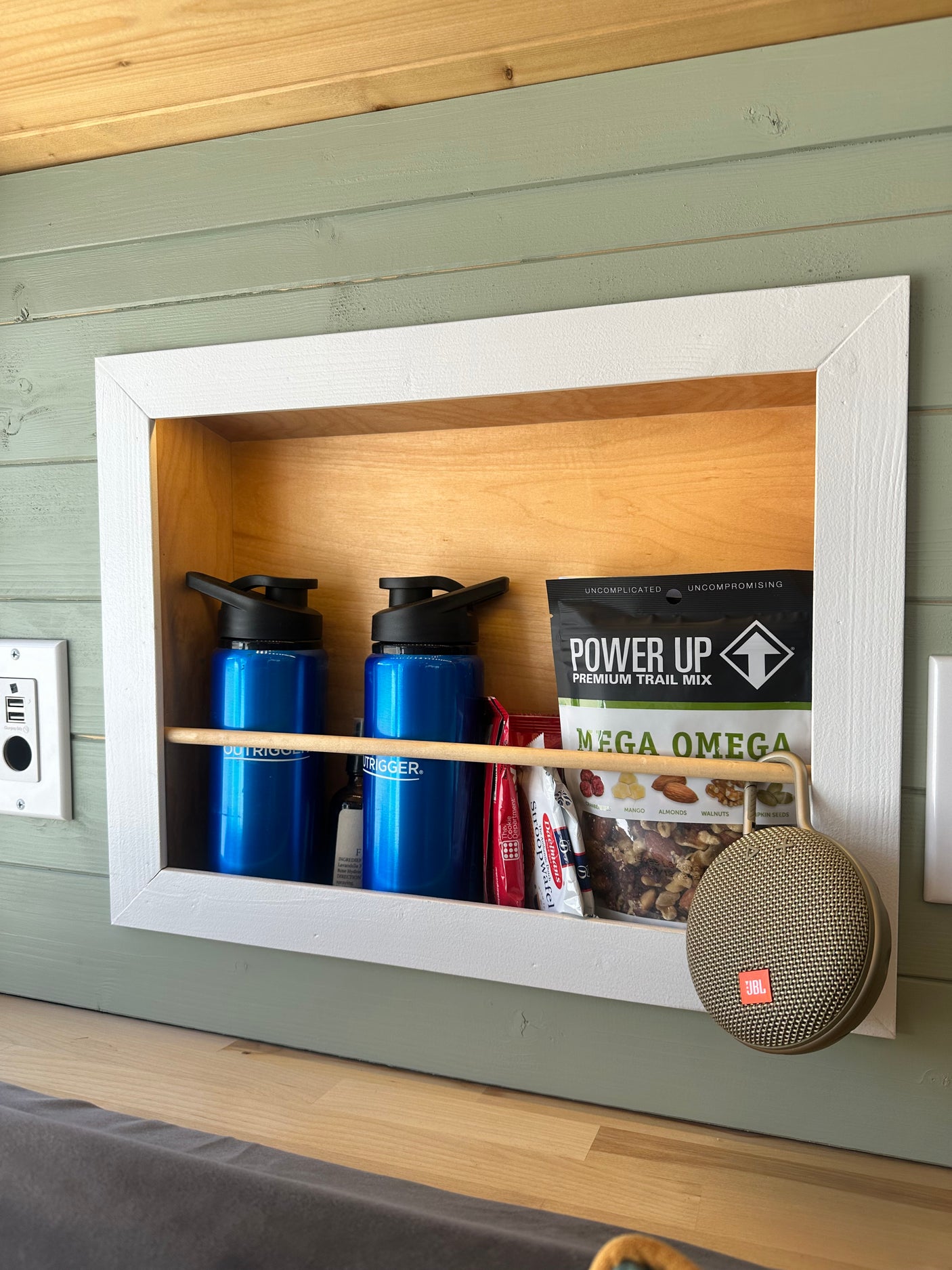 Stay organized in your RV rental with this built-in cubby holding water bottles, snacks, and a portable JBL speaker.