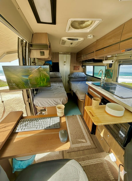 This inviting RV rental features a workstation, cozy beds, a kitchen, and a stunning ocean view, perfect for remote work.
