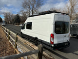White Ford Transit camper van, perfect for an RV rental, parked on a suburban street.