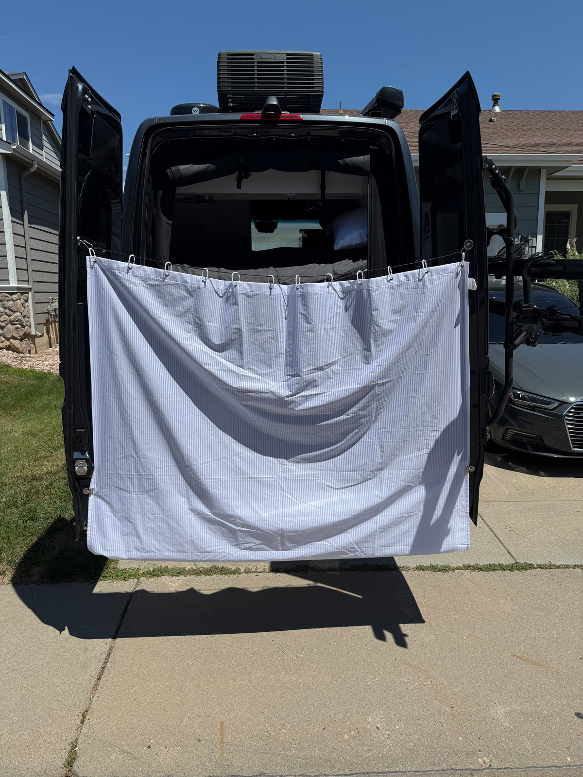 RV rental van with privacy curtain for outdoor shower, parked in driveway on a sunny day. — photo 8