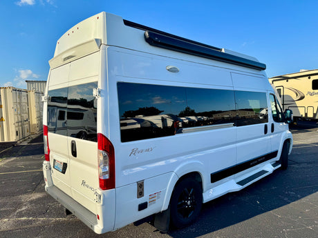 White Regency National Traveler camper van for rv rental, parked in a sunny lot with other RVs.