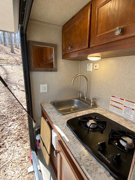 Explore this RV rental's efficient kitchen setup, complete with a sink, Suburban stove, and storage.