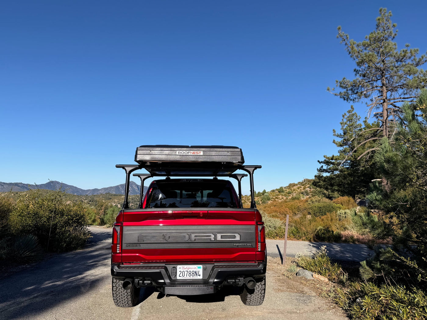  ready for your next RV rental camping adventure.|This red truck features an interior Havnby inflatable bed and an exterior rooftop tent. A versatile setup for overlanding or as an rv rental alternative.|Red Ford Raptor truck with an open rooftop tent & ladder in a scenic setting. Ideal for an adventurous RV rental experience.|Discover this red Ford Raptor — photo 15