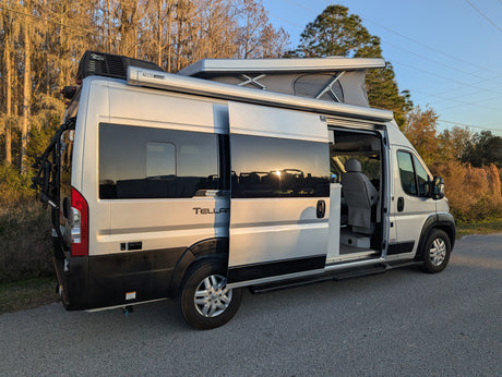 Silver Tellaro pop-top camper van with side door open, ready for your RV rental adventure. Bike rack & awning visible.