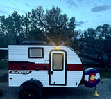 This compact Sunray Sport travel trailer, white with red stripes, is parked at a campsite. Ideal for your next RV rental adventure.