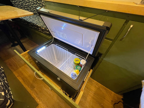 Smart RV rental setup: a built-in pull-out portable fridge/freezer, lit for easy access to camping essentials.